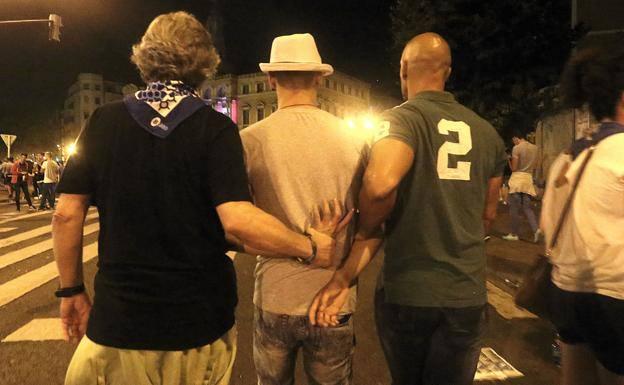 Dos agentes de paisano se llevan a un detenido.