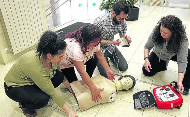 Varias personas practican con un muñeco la maniobra de colocación de un desfibrilador.