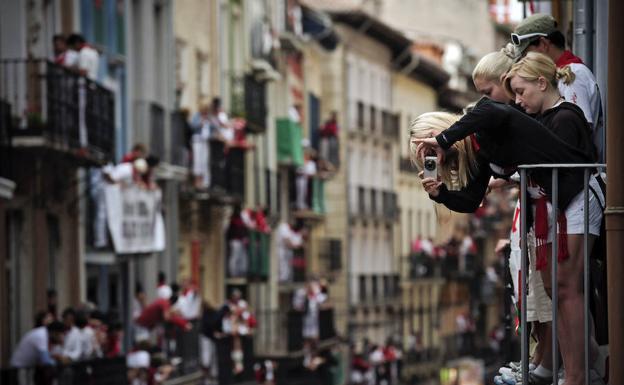 Turistas sacan fotos del encierro desde un balcón./AP