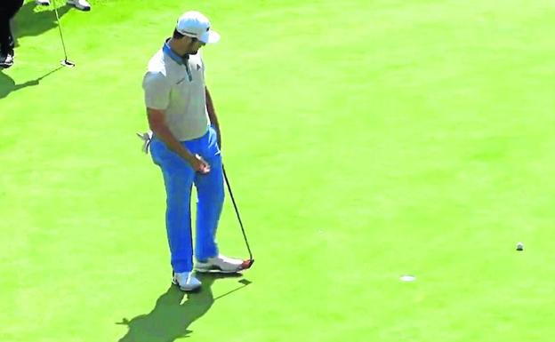 Jon Rahm mira atónito a la bola tras el tercero de los cuatro putss que necesitó para cerrar el primer hoyo con doble bogey./pga