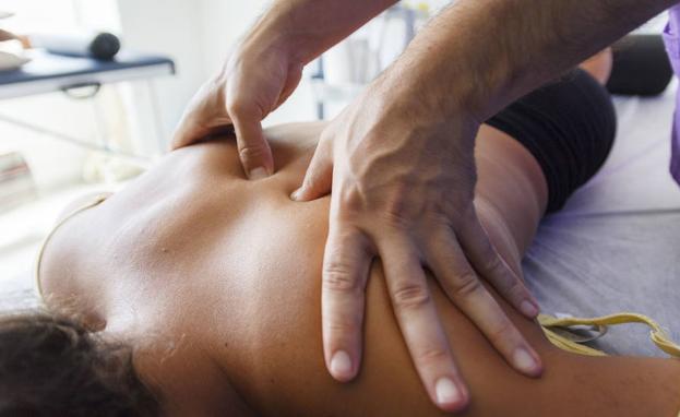 Un fisioterapeuta realiza un masaje en la espalda./Fotolia