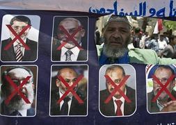 Un ciudadano sostiene una pancarta con fotos del antigu Gobierno. / Ap | Atlas/