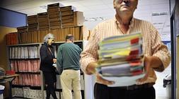 Un funcionario traslada expedientes mientras la magistrada Biurrun consulta documentos./ Ignacio Pérez/