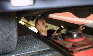 Un mecánico revisa los bajos de un vehículo en una estación ITV. :: E. C./