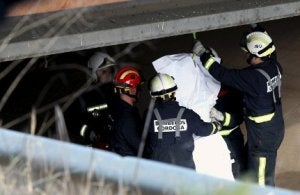Bomberos descuelgan el cuerpo del joven, debajo de un puente. :: EFE/