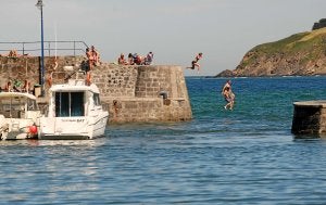 Bañistas se lanzan al gua desde el muelle de Mundaka, donde hay atracadas varias embarcaciones de recreo. :: PEDRO URRESTI/