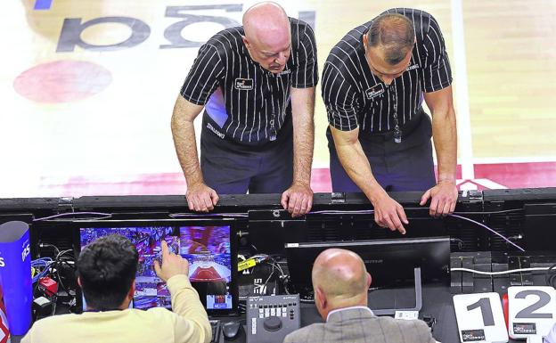 Two referees approach the table to review an action in the 'Instant Replay'. 