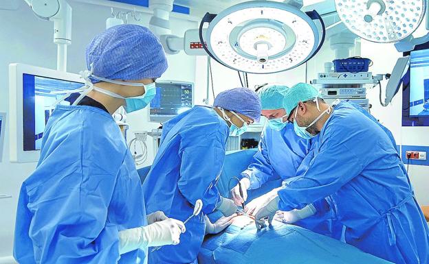Several surgeons operate on a patient in a hospital operating room. 