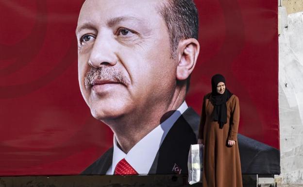 Una mujer con velo se detiene ante una fotografía del presidente turco, Recep Tayyip Erdogan, en Estambul./EFE