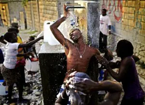 Una ducha bajo un grifo en plena calle se puede considerar un gran lujo para los habitantes de Puerto Príncipe. :: AP/RODRIGO ABD/